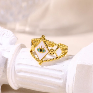 Detail view of gold evil eye ring with white enamel on a decorative stone column