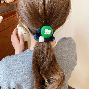 Détail du chouchou en tissu bleu foncé avec breloque m verte et perle sur queue de cheval
