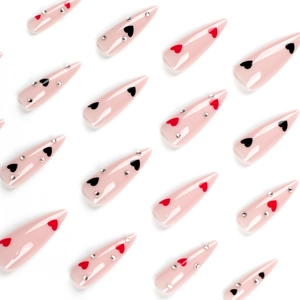 Long stiletto press-on nails in nude pink with red black heart patterns and rhinestones