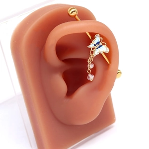 Golden industrial barbell featuring a blue enamel butterfly and pink crystal tassel