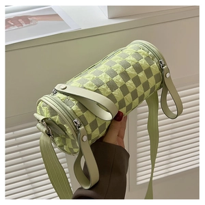 Detailed view of light green checkerboard cylinder bag with wide nylon strap and double zipper