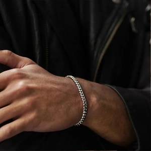 Close-up of a silver NK curb chain bracelet worn on a wrist with a black leather jacket