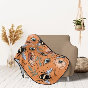 Detailed texture of orange flannel throw blanket with bee and eye surrealist patterns