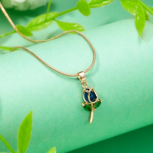 Detailed close-up of a gold tulip pendant with blue enamel petals on a green pillar
