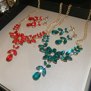 Detailed close-up of floral crystal necklace and earrings in red and emerald green stones
