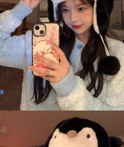 Detail of plush blue sweater and penguin earflap hat with soft long faux fur material