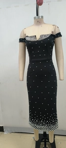 Détail d'une robe noire à épaules dénudées avec perles blanches sur tissu mat