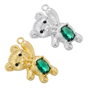 Close-up of gold and silver bear pendants with green zirconia inlay on white background