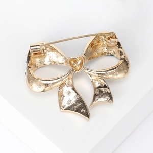 Elegant gold bow brooch with intricate floral pattern texture and secure safety pin back
