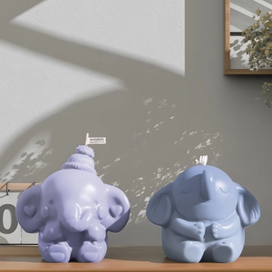 Detail of cute handmade elephant candles in purple and blue on a minimal wooden shelf