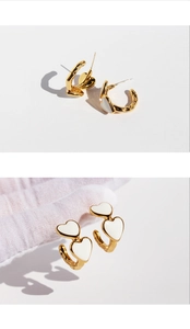Macro detail of vintage gold heart earrings with white enamel finish and textured surface