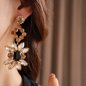 Gros plan d'un mannequin portant des boucles d'oreilles vintage fleurs dorées et marron