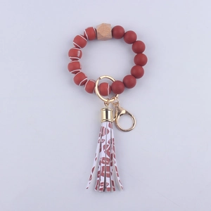 Dettaglio portachiavi con perle in silicone rosso e marrone e nappa in pelle PU decorativa