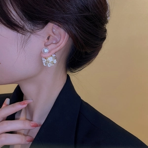 Gros plan de boucles d'oreilles élégantes avec fleurs et perles portées par un mannequin
