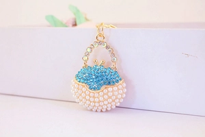 Close-up of gold handbag keychain with blue rhinestones and white pearls detail