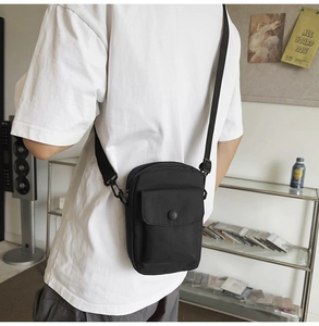 Model view showing the back profile of a compact black crossbody bag with adjustable strap