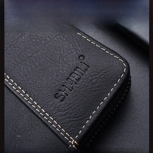 Macro shot of litchi grain black leather wallet with white stitching and embossed logo
