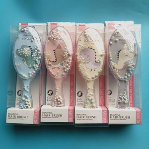 Detail of four colorful dinosaur sequin hair brushes in individual transparent packaging