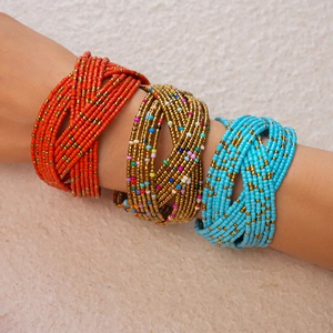Macro detail of multi-strand bohemian glass bead bracelets in red, gold, and blue