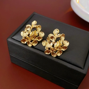 Detailed close-up of golden floral stud earrings with textured finish on a jewelry box