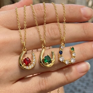 Detailed view of U-shaped horseshoe necklaces with colorful zircon stones in gold finish