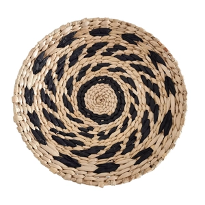 Dettaglio decorazione murale boho intrecciata con motivi a spirale neri e fibre naturali