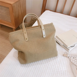 Close-up of woven canvas tote texture with leather handles and metallic rivet details