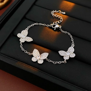 Detailed shot of silver butterfly bracelet with three rhinestone pendants on black tray