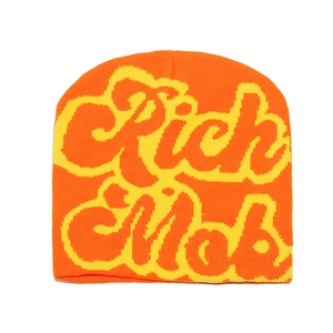 Close-up of orange knit beanie featuring yellow Rich Mob embroidery in street style