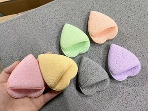 Detail of heart-shaped facial sponges in multiple colors with finger pocket design