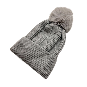 Vue détaillée du bonnet d'hiver gris en maille torsadée avec pompon en fourrure