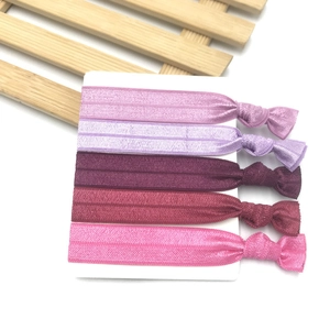 Detailed view of five colorful knotted elastic hair ties on a white card display