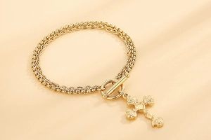 Detail of double-layer gold chain bracelet with rose cross pendant and OT toggle clasp