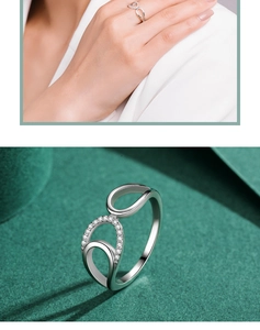 Close-up of geometric hollow silver ring with sparkling stones on textured green surface