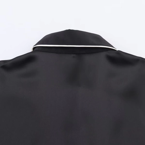 Detail of black satin shirt collar with white contrast piping and smooth stitching