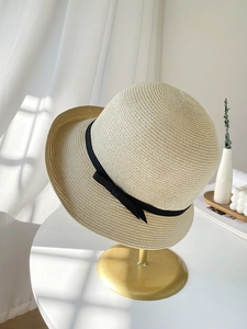 Close-up of fine straw texture and black bow detail on a minimalist sun hat