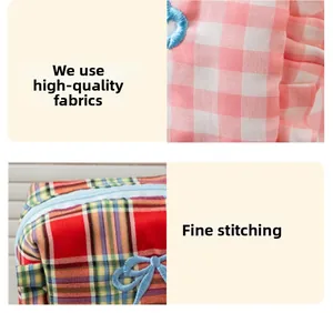 Detailed close-up of plaid fabric texture and delicate floral embroidery with fine stitching