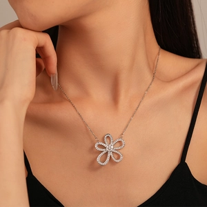 Detail of silver hollow flower pendant necklace with zircon pavé worn on neck