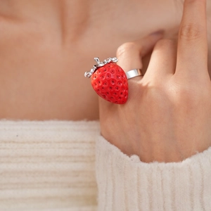 Dettaglio dell'anello a fragola in resina rossa con foglie argentate, stile gioiello chic