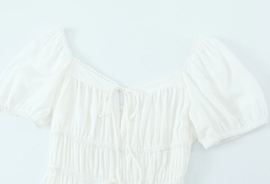 Détail d'une robe française blanche montrant des manches bouffantes et dentelle fine
