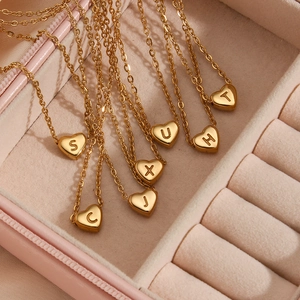 Colliers avec pendentifs coeur dorés et initiales dans un écrin en velours rose