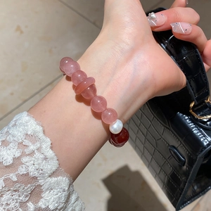 Detail of beaded bracelet with strawberry quartz, red agate and a white freshwater pearl