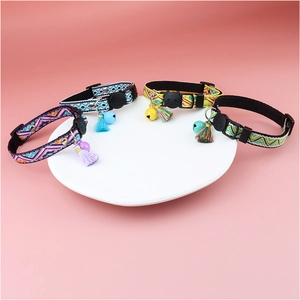 Detail of four colorful plaid cat collars with bells and tassels on a white tray