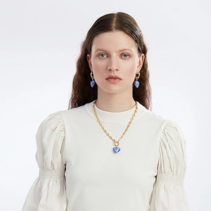 Mannequin portant un collier doré et des boucles d'oreilles avec cœurs en verre bleu