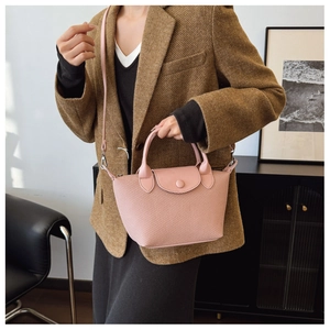 Detail of pink dumpling-shaped bag with woven texture and adjustable shoulder strap