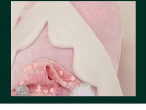 Close-up of pink sequin Christmas stocking with white wavy trim and decorative pom poms