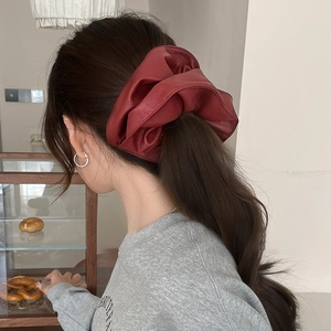 Chouchou géant vintage en similicuir rouge présenté sur une coiffure élégante de côté