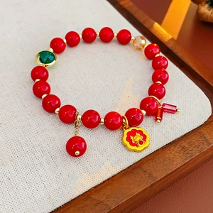 Détail d'un bracelet en perles rouges avec pendentif dragon doré et perle verte