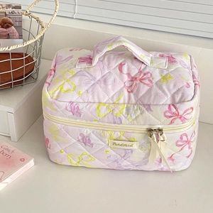 Close-up of quilted purple butterfly makeup bag with ribbon zipper and handle