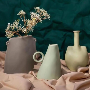 Primer plano de jarrones de cerámica mate con formas únicas sobre tela elegante